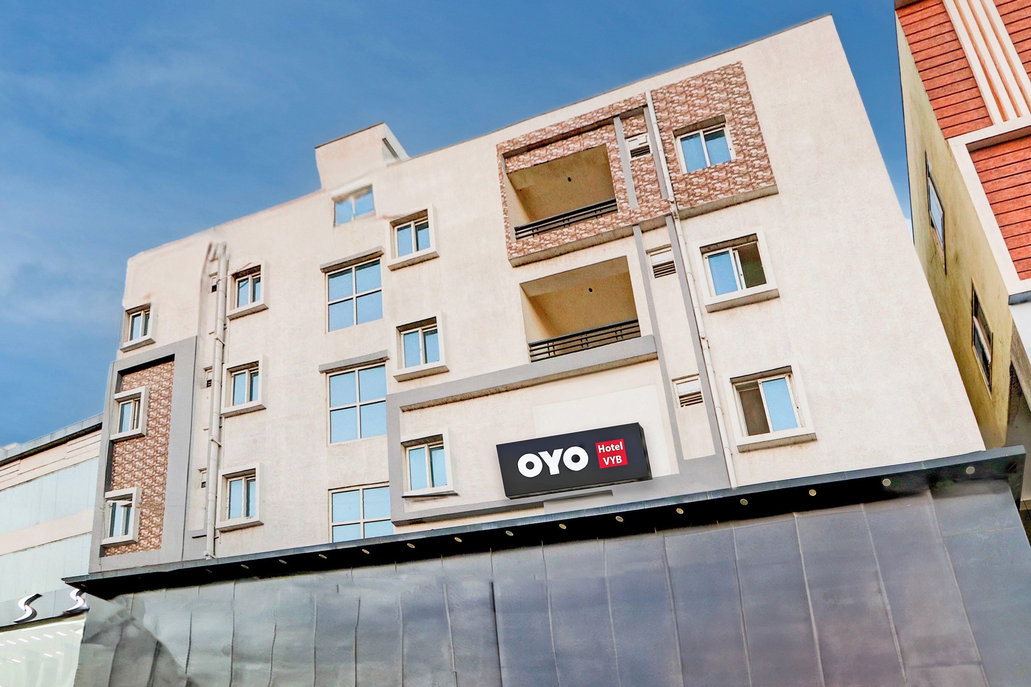 Um edifício de hotel com vários andares e uma placa com a inscrição 'OYO Hotel Vyb'.