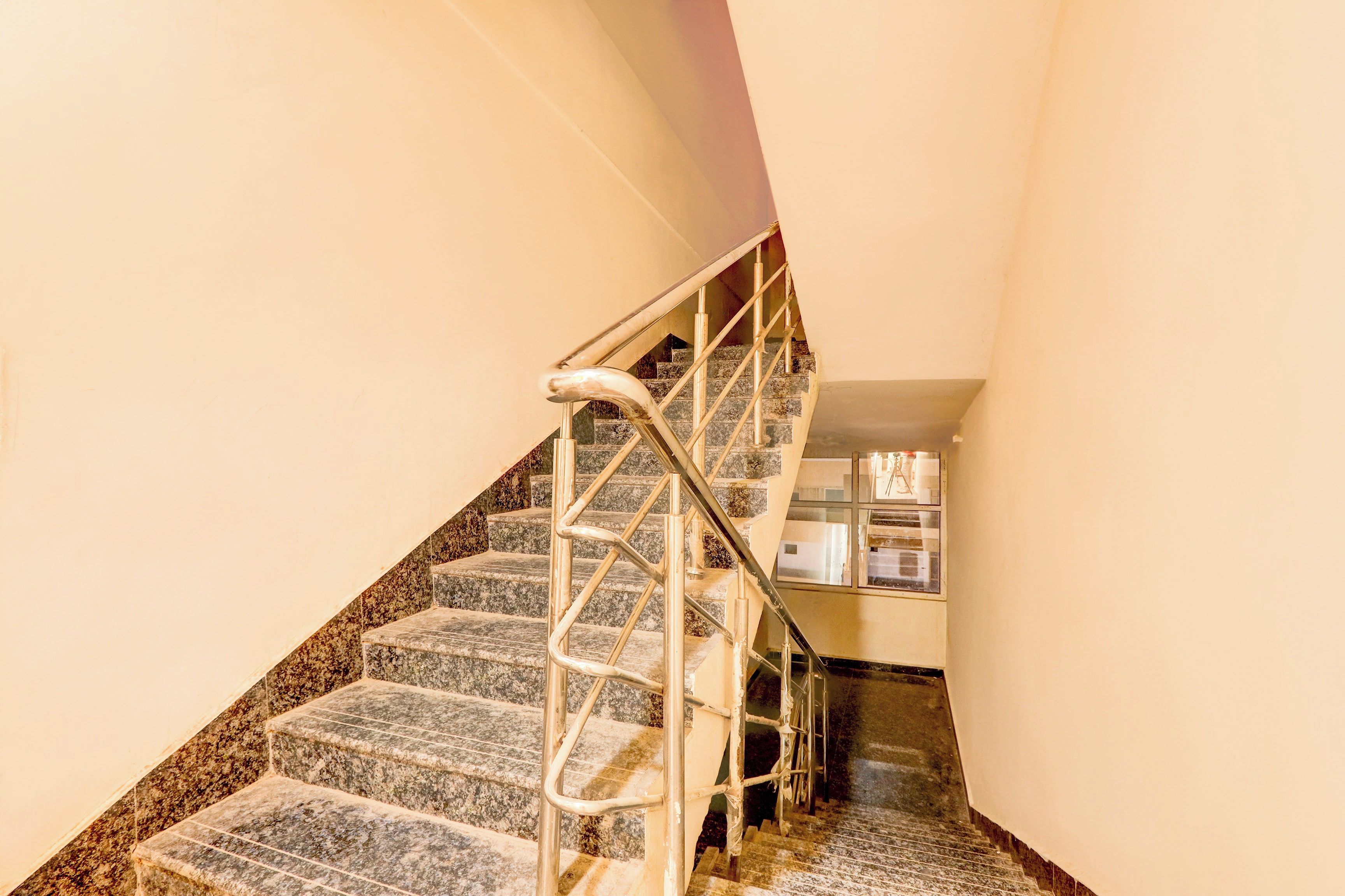 Escadaria com grades de metal e degraus de granito que levam a um patamar.
