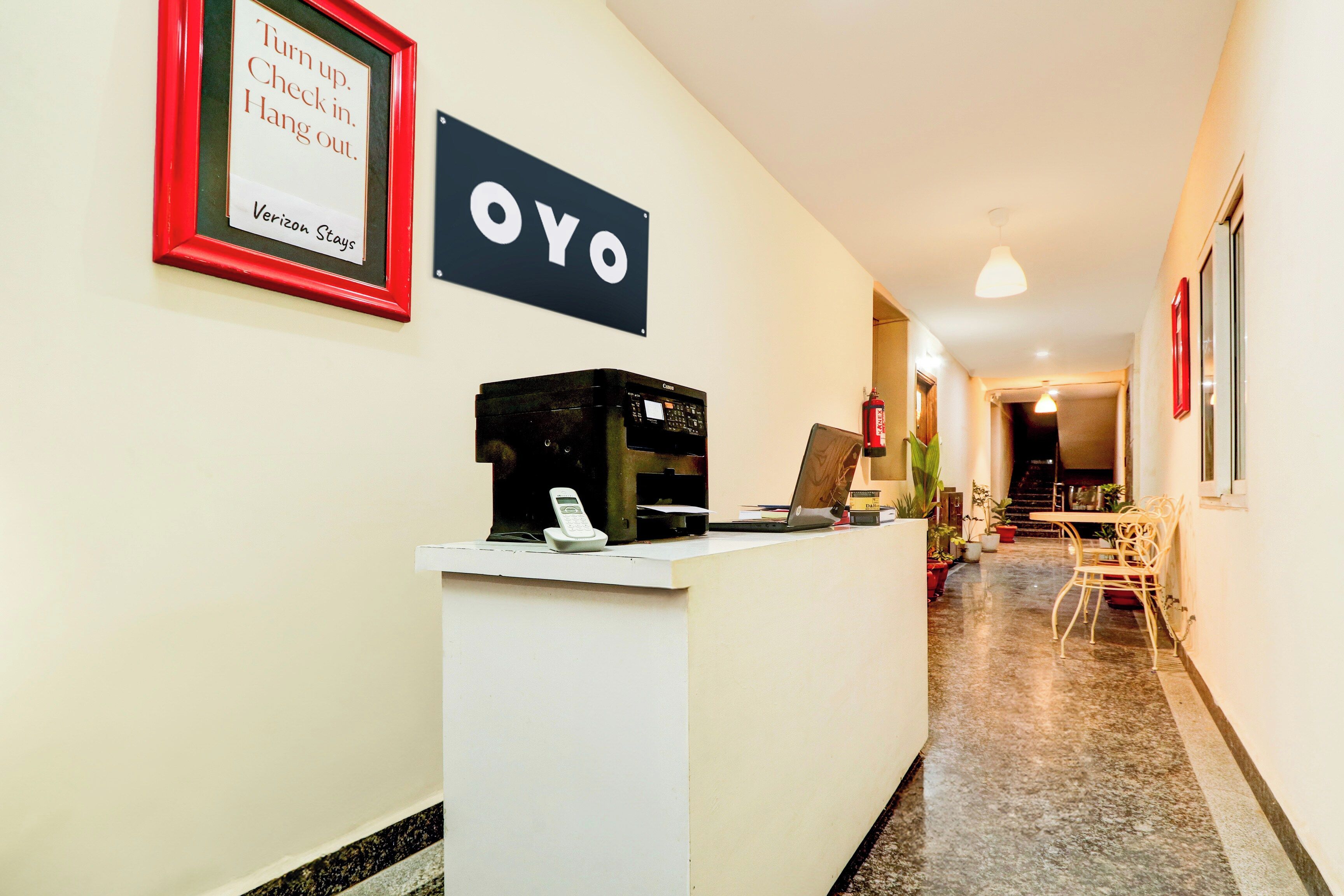 A hotel reception area with a sign that reads 'OYO' and a framed sign above it that says 'Turn up. Check in. Hang out.'