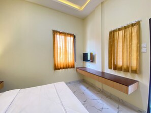 Een hotelkamer met een bed, een aan de muur bevestigde televisie en een houten console.