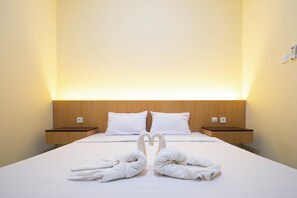 Una habitación de hotel con una cama bien tendida, dos mesitas de noche y un cabecero.