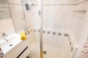 A bathroom with a glass shower enclosure, a sink, and a mirror. - Cozy House, Town Center, 7 min Beach by Groom* (Ploemeur)