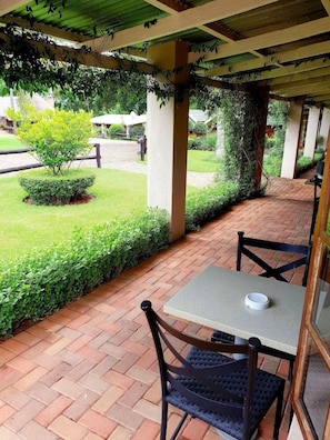 An outdoor patio with a table and chairs, surrounded by a brick floor and greenery. - Haggards on Hilldrop (Newcastle)