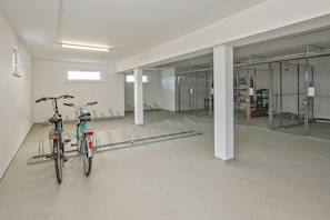 Ein sauberer, moderner Innenraum mit einem Fahrradständer, einem Fahrrad und einem durch Glasabtrennungen versehenen Bereich mit Metallkäfigen.
