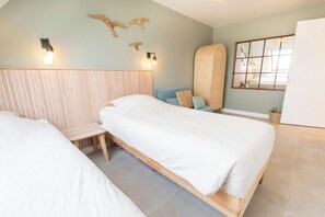 Ein Schlafzimmer mit zwei Betten, einem Holzkopfende, Wandleuchten und einem großen Spiegel.