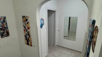 Un couloir avec une porte blanche, un miroir et des œuvres d’art accrochées aux murs.