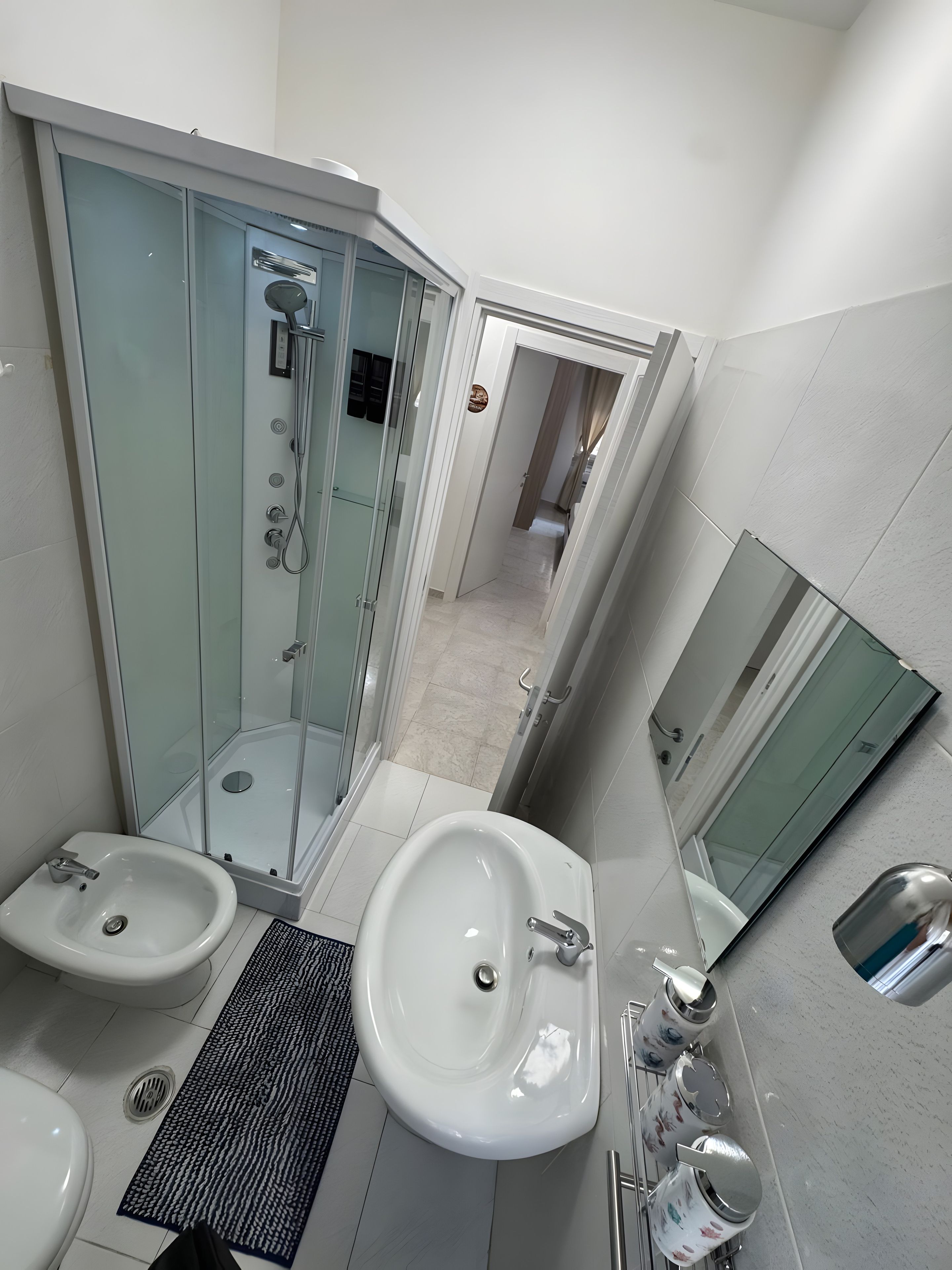 Ein modernes Badezimmer mit einer gläsernen Duschkabine, zwei Waschbecken und einem großen Spiegel.