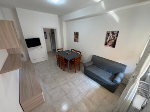 A compact living space with a dining area, a sofa, and a TV mounted on the wall. - Holiday Home 'De Rosa'S Home 2' with Private Terrace, Wi-Fi and Air Conditioning (Tortora Marina)