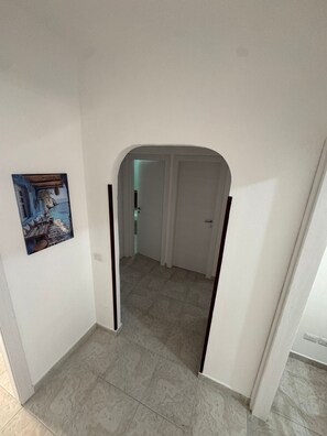 A hallway with a door leading to a room, a tiled floor, and a painting on the wall. - Holiday Home 'De Rosa'S Home 2' with Private Terrace, Wi-Fi and Air Conditioning (Tortora Marina)