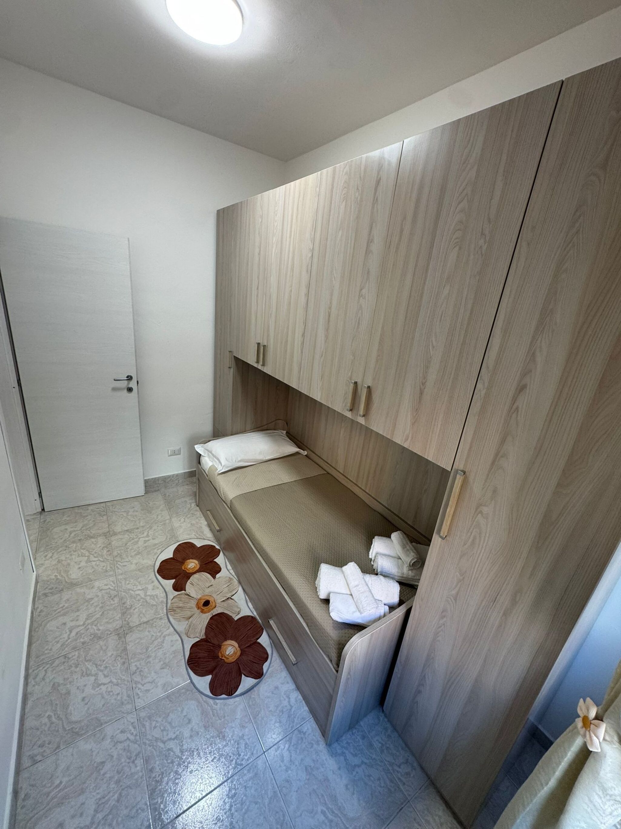 Una camera compatta con un letto, armadietti e un angolo bagno.