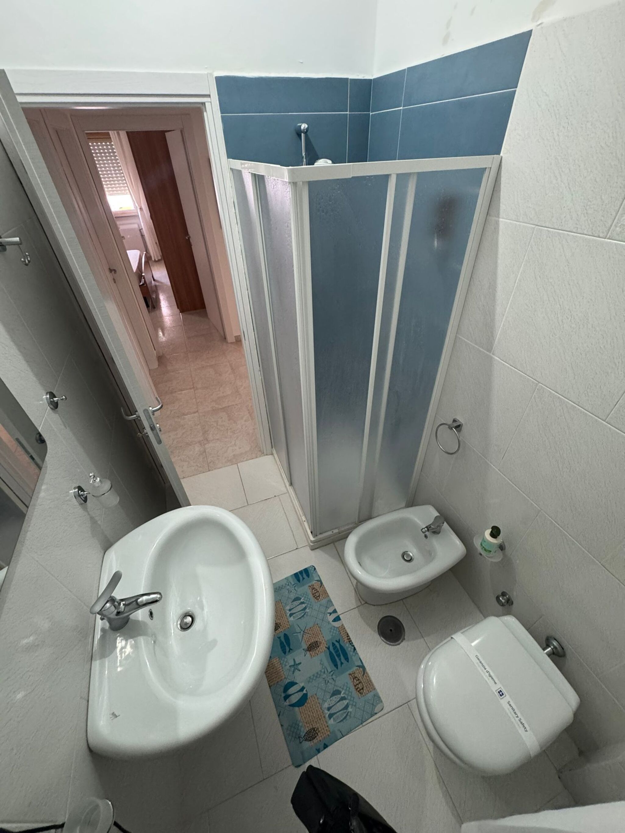 Ein Badezimmer mit Duschkabine, zwei Waschbecken und einem Bidet.