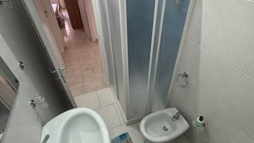 Ein Badezimmer mit Duschkabine, zwei Waschbecken und einem Bidet.