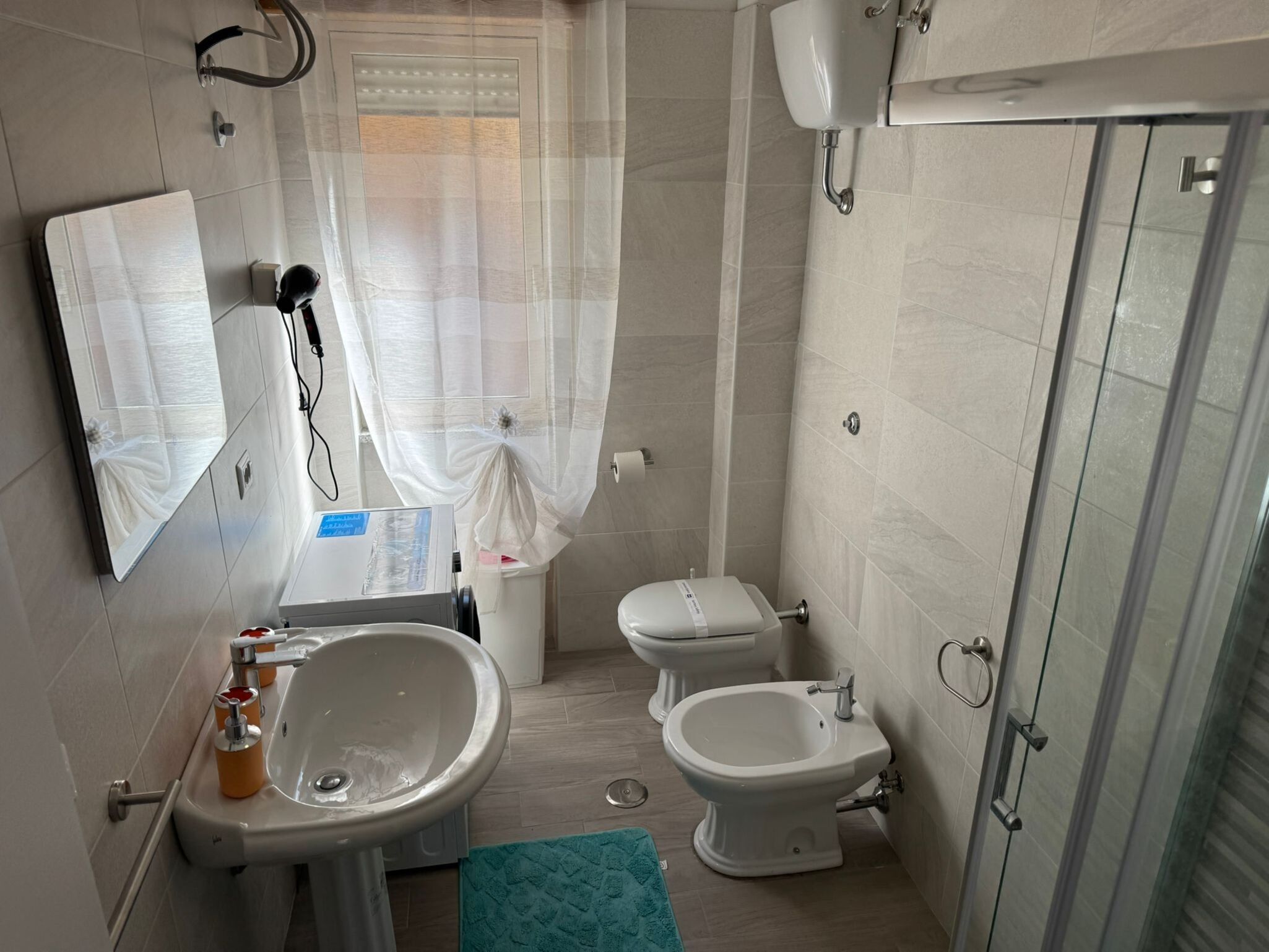 Ein Badezimmer mit Waschbecken, zwei Toiletten, einer Dusche und einem Spiegel.