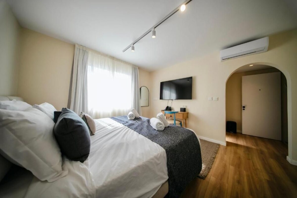 Un dormitorio con cama, televisor, puerta y aire acondicionado.