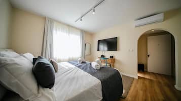 Un dormitorio con cama, televisor, puerta y aire acondicionado.