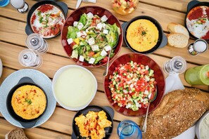 A variety of dishes including a salad, soup, and bread on a wooden table. - LiBa (Chlorakas)
