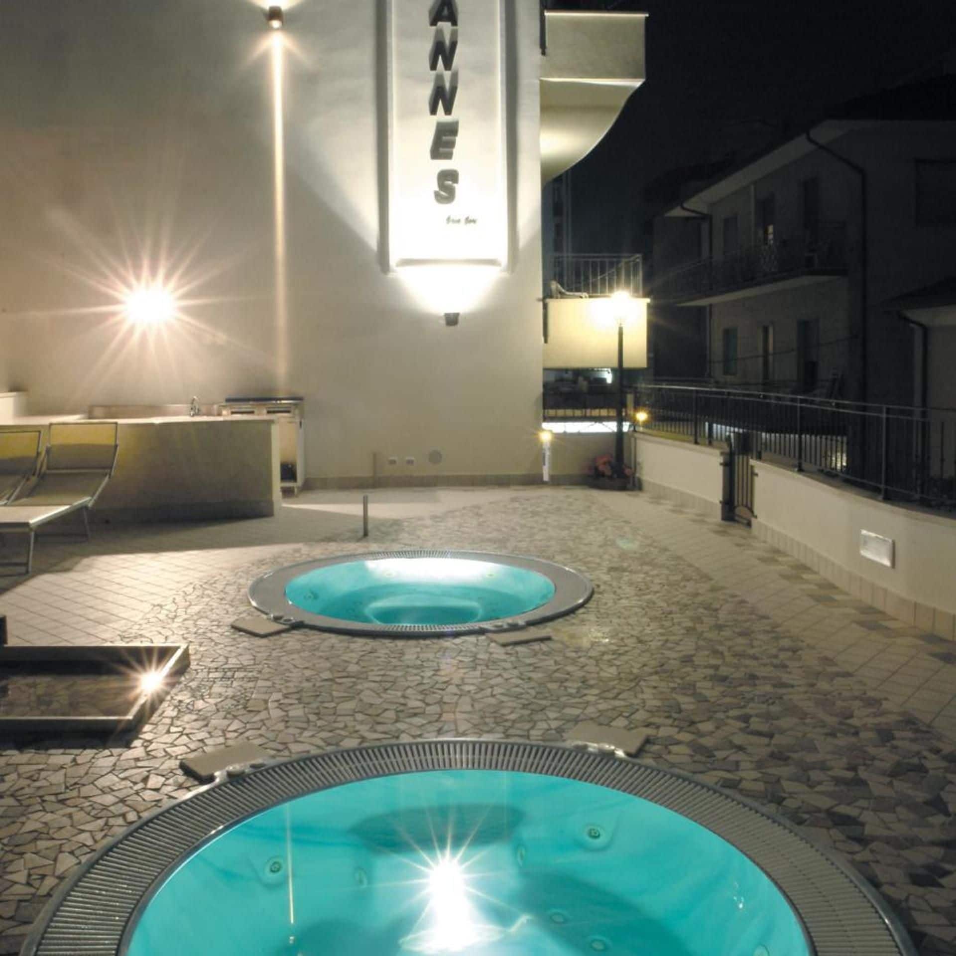 A pool area with two hot tubs, a reception desk, and a staircase leading to an upper level.