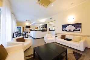 A hotel lobby with a reception desk, seating area, and a painting of an orchid. - Hotel Galassia (Rimini)