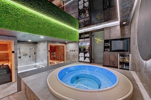 A spa area with a hot tub, a green wall, and a television. - Wellness Hotel Fenix Liberec (Liberec)