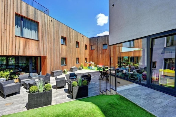 Un patio exterior moderno con mobiliario y jardineras.