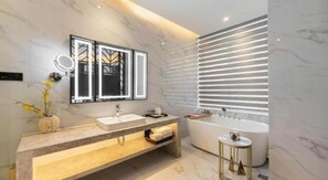 Un baño moderno con una bañera independiente, un tocador con espejo y un aplique en la pared.