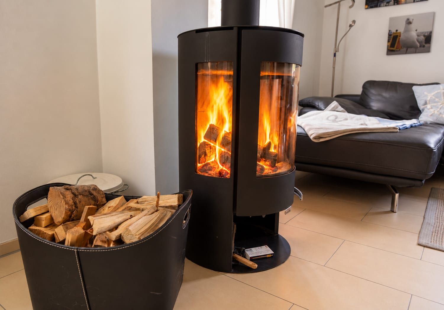 A modern living room with a black wood-burning stove, a leather sofa, and a coffee table.