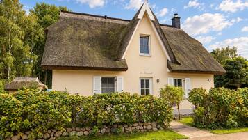A traditional house with a steeply pitched roof, a stone wall, and a well-maintained garden.