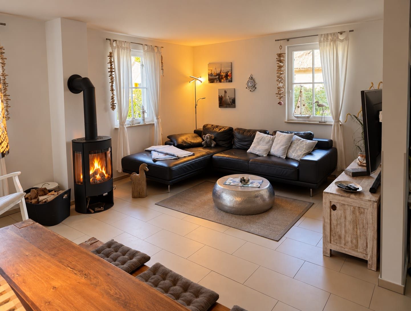 Ein gemütliches Wohnzimmer mit Kamin, einer Eckcouch, einem Holztisch und einem Fernseher.