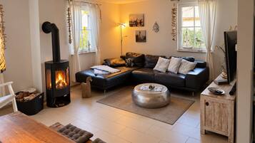 A cozy living room with a fireplace, a sectional sofa, a wooden coffee table, and a television.