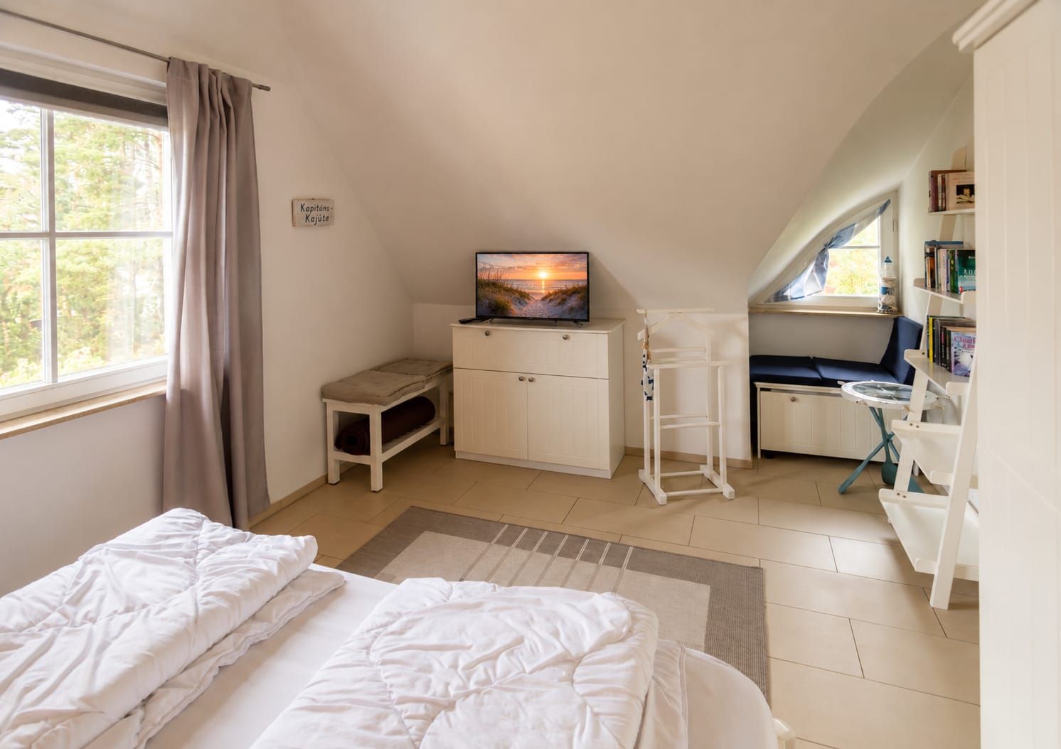 Ein Schlafzimmer mit zwei Betten, einem Fernseher, einem Schreibtisch und einem Bücherregal.