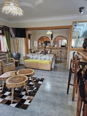 Un amplio espacio de sala con un sofá, mesas redondas y una mesa de comedor.