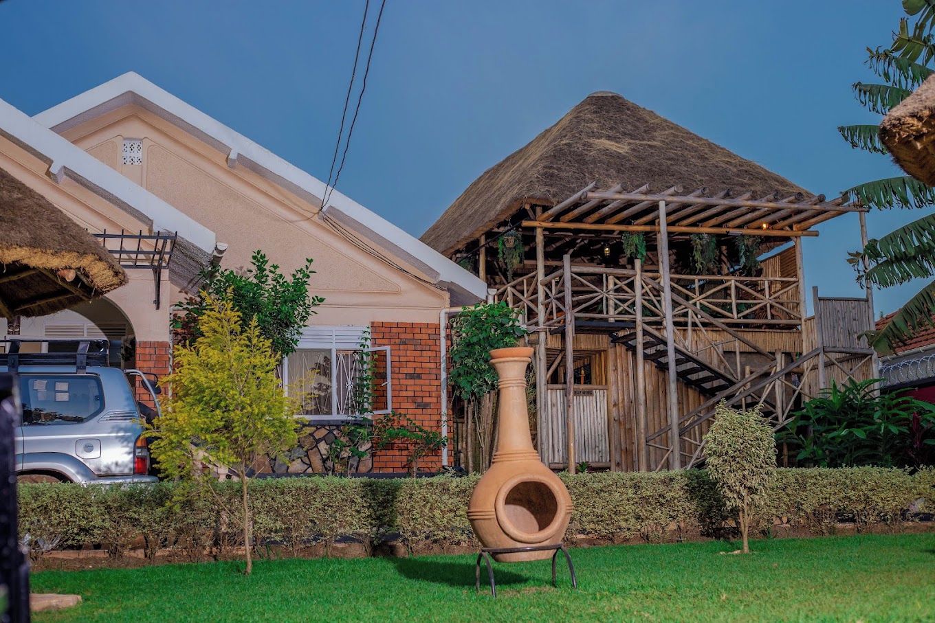 A house with a thatched roof, a brick exterior, and a wooden structure with a staircase.