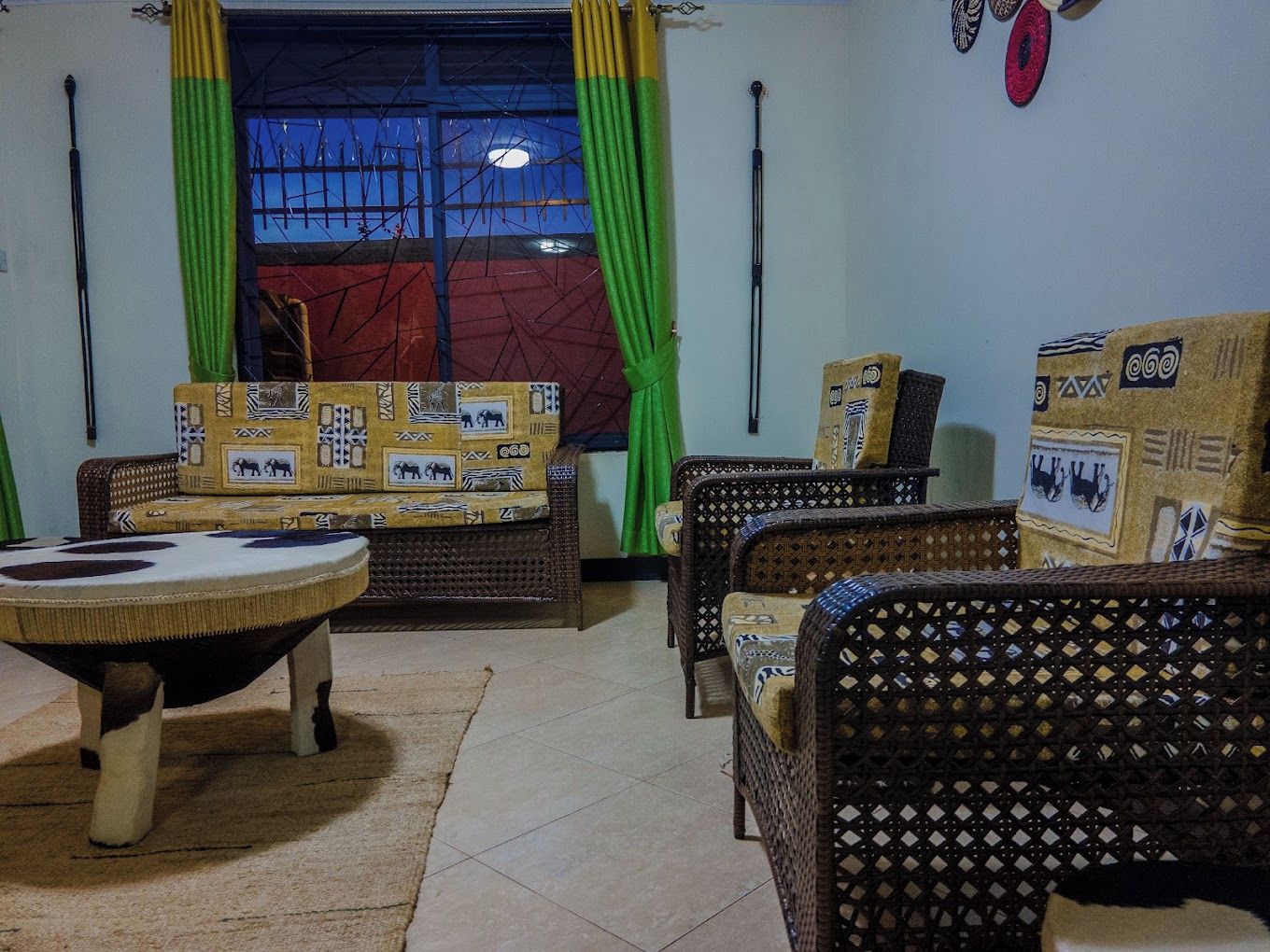 Una habitación con sofá, dos sillones, una mesa redonda y un tapete estampado.