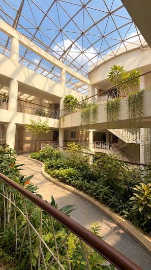 A multi-level atrium with a glass ceiling, indoor plants, and a central staircase. - RapidNest Jakkur A Luxury Stay with Jacuzzi (Bangalore)