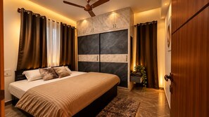 Quarto com cama, cortinas, ventoinha no teto e um grande armário embutido.