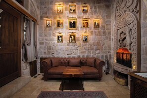 Una habitación con paredes de piedra, un sofá de cuero, una mesa de centro de madera y una chimenea con un revestimiento decorativo.