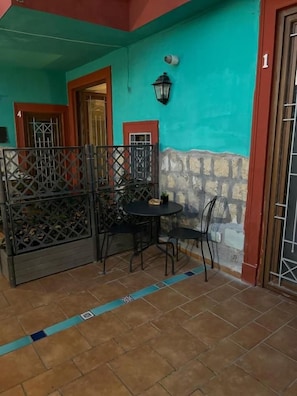 Un patio con mesa y sillas, una cerca decorativa y una puerta con el número 1.