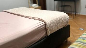 Een slaapkamer met een bed, een stoel, een bureau en een spiegel.