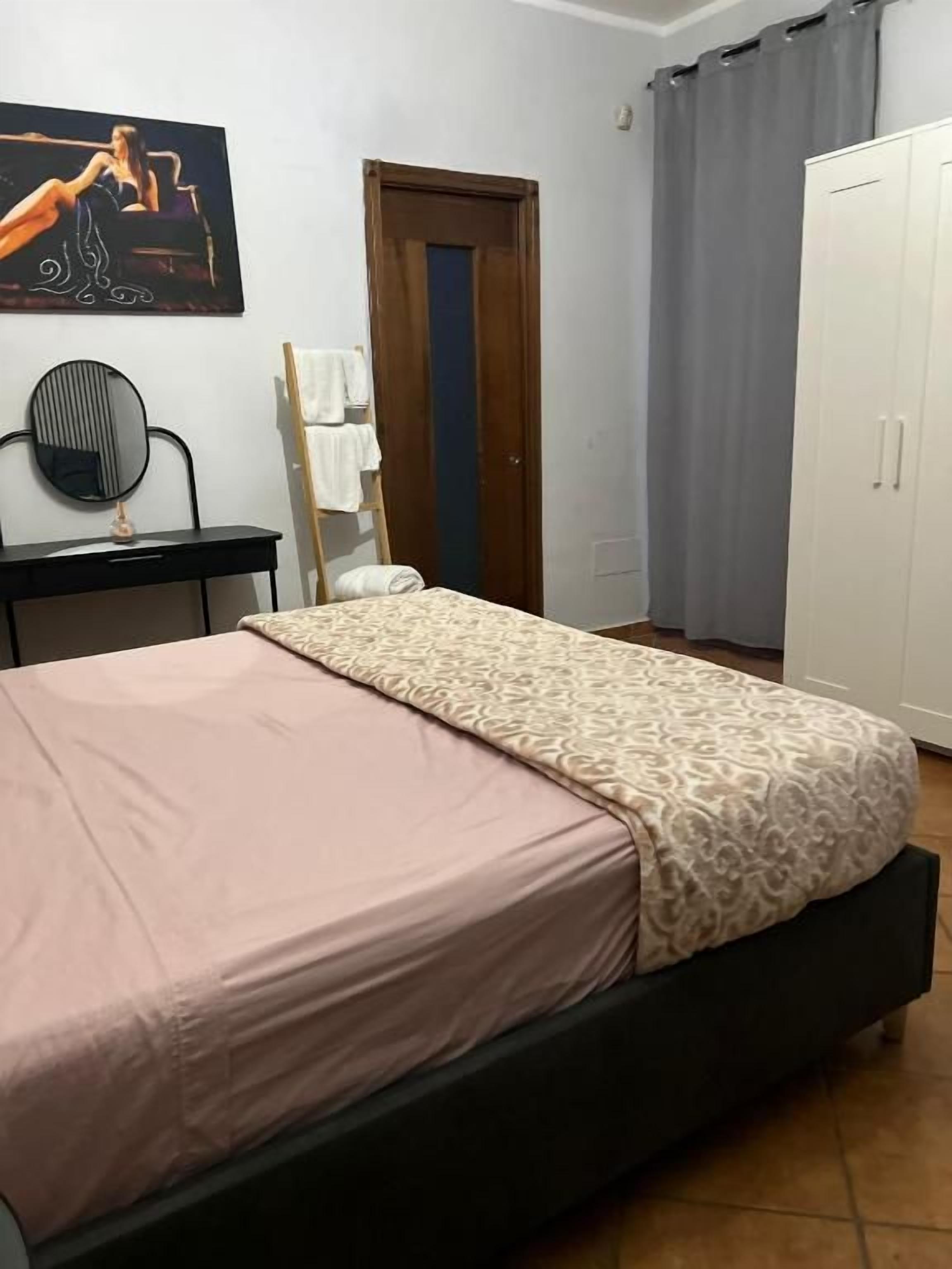 Ein Schlafzimmer mit einem Bett, einem Kleiderschrank, einem Spiegel und einem Bild an der Wand.