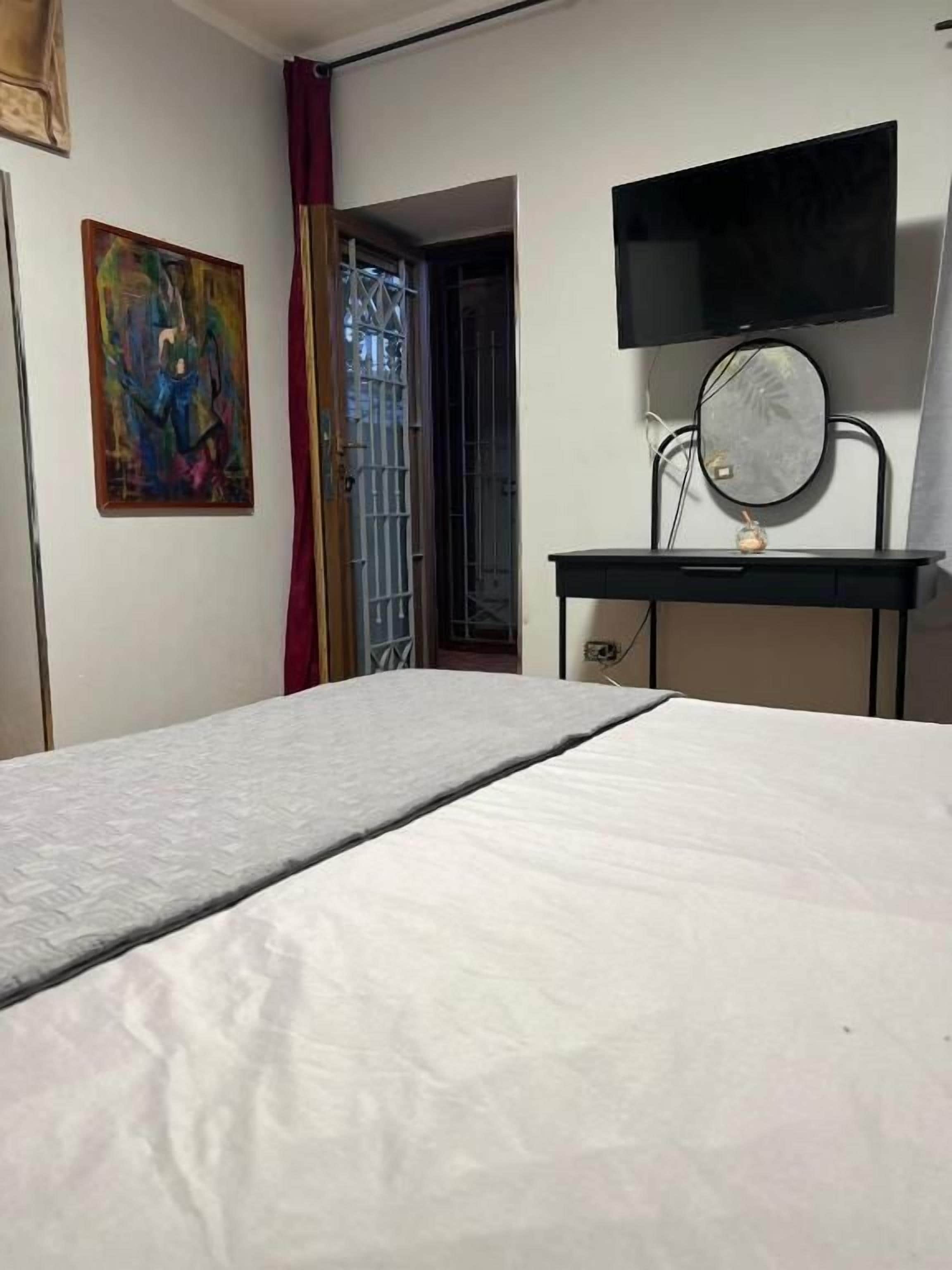 Een slaapkamer met een bed, een aan de muur bevestigde televisie en een deur die naar een andere kamer leidt.