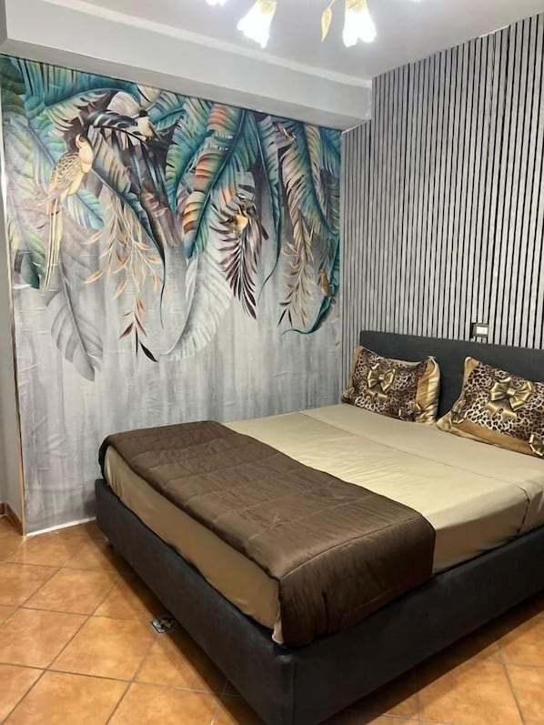A bedroom with a bed, a wall with vertical lines, and a large mural with birds and foliage.