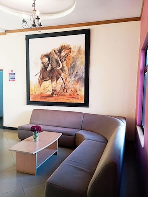 A modern interior with a large sectional sofa, a coffee table, and a framed artwork of an elephant. - Sigona Golf Club (Kikuyu)