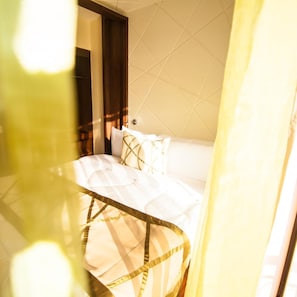 A hotel room with a bed, a nightstand, and a window with curtains. - Sigona Golf Club (Kikuyu)