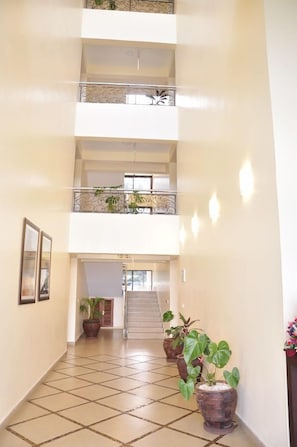 A multi-level interior with a central staircase, potted plants, and a tiled floor. - Sigona Golf Club (Kikuyu)