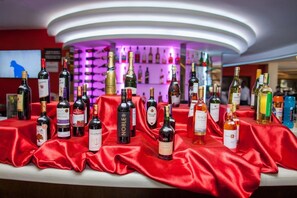 A bar area with a variety of bottles displayed on a red cloth-covered table. - Sigona Golf Club (Kikuyu)
