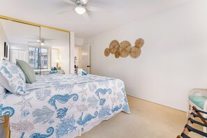 A bedroom with a bed, a chair, a ceiling fan, and a wall decoration. - Hale Kamaole 244 - Modern Suite next to Beach (Kihei)