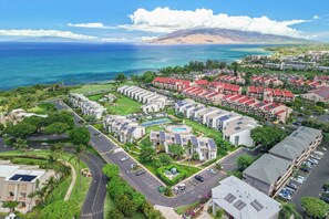 Un quartier résidentiel situé sur la côte, composé de plusieurs immeubles d’appartements, doté d’une piscine centrale et offrant une vue sur l’océan.