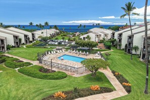 A resort with a swimming pool, lounge chairs, and a view of the ocean. - Hale Kamaole 244 - Modern Suite next to Beach (Kihei)