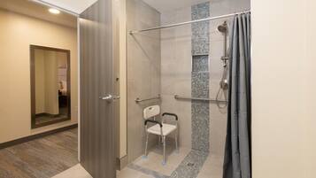 Une salle de bain moderne dotée d’une douche à l’italienne, d’une barre d’appui et d’un banc accessible aux personnes en fauteuil roulant.