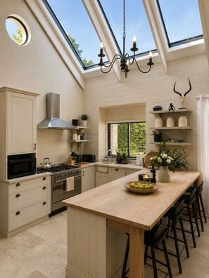 A modern kitchen with a skylight, a central island, and bar stools. - 10 sleeper villa with daily housekeeper -near vineyard (Cape Town)